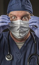 Determined looking male doctor or nurse with protective wear and stethoscope