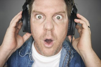 Shocked man wearing headphones against a grey background