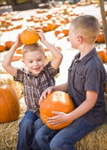 Two boys at the pumpkin patch talking about their pumpkins and having fun on a fall day