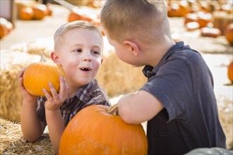 Two boys at the pumpkin patch talking about their pumpkins and having fun on a fall day
