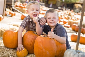 Two boys at the pumpkin patch with thumbs up and having fun on a fall day