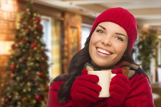 Warm mixed race woman wearing winter hat and gloves in christmas setting