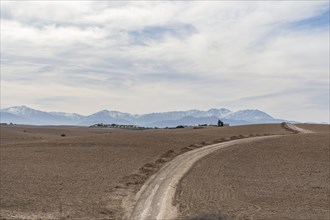 Dirt road through Agafay desert leading to Atlas Mountains