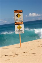 Surf and currents warning sign on a beach in hawaii