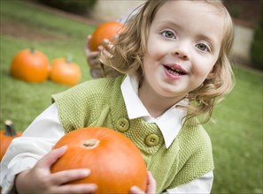 Adorable young child girl enjoying the pumpkins at the pumpkin patch