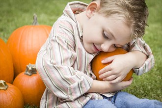 Adorable young child boy enjoying the pumpkins at the pumpkin patch