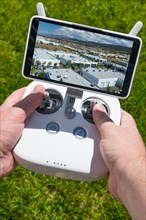 Hands holding drone quadcopter controller with indutrial buildings on screen