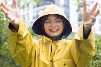 Happy young woman with yellow rain jacket with hood
