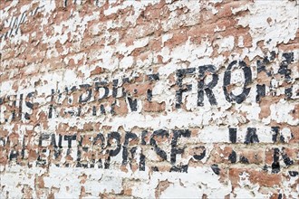 Old weathered brick wall with decaying advertisement writing