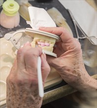 Female dental technician applying porcelain to A 3D printed implant mold in the lab