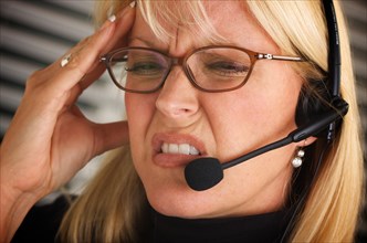 Businesswoman with phone headset show signs of having a headache