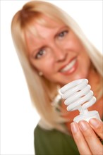 Attractive blonde woman holds energy saving light bulb isolated on a white background with narrow depth of field