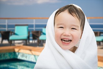 Happy cute mixed-race chinese and caucasian boy on cruise ship wrapped in A towel