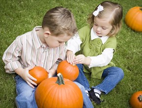 Cute young brother and sister children enjoying the pumpkins at the pumpkin patch