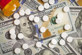 Medicine pills scattered on newly designed U.S. one hundred dollar bills