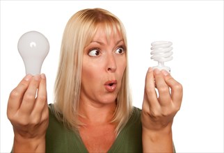 Funny faced woman holds energy saving and regular light bulbs isolated on a white background