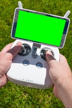 Hands holding drone quadcopter controller with blank green screen