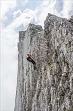 Young man climbing a vertical rock face without a rope