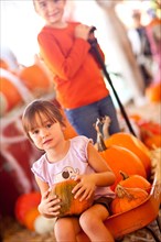Cute girl riding A wagon with her pumpkin and sister at A pumpkin patch one fall day