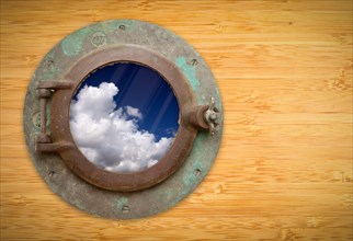 Antique porthole on bamboo wall with view of beautiful blue sky and clouds