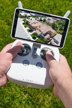 Hands holding drone quadcopter controller with residential homes on screen