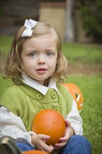Adorable young child girl enjoying the pumpkins at the pumpkin patch