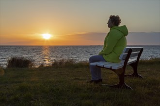 Woman enjoying the sunset on a bench