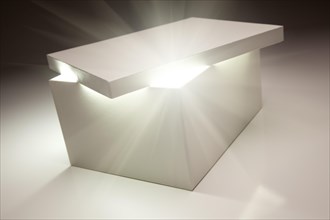 White box with lid revealing something very bright on a grey background