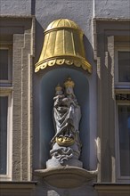 Sculpture of Maria immaculata under a gilded canopy on a residential building
