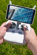 Hands holding drone quadcopter controller with corporate building on screen