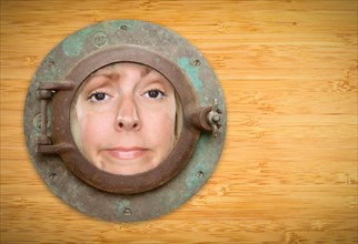 Antique porthole on bamboo wall with funky woman looking through the window