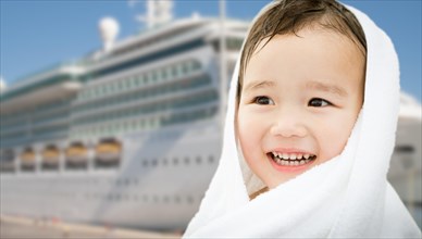 Happy mixed-race chinese and caucasian boy near cruise ship wrapped in A towel