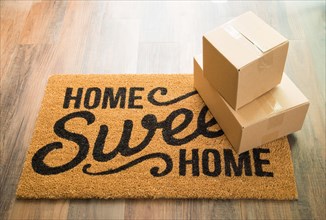 Home sweet home welcome mat on wood floor with shipment of boxes