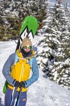 Young man with snowboard on his back