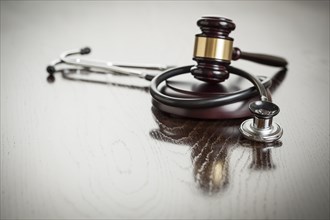 Gavel and stethoscope on reflective wooden table