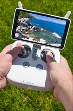 Hands holding drone quadcopter controller with beautiful lake view on screen