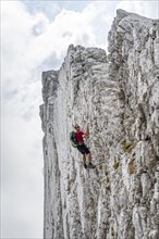 Young man climbing a vertical rock face without a rope