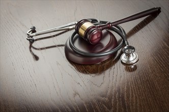 Gavel and stethoscope on reflective wooden table