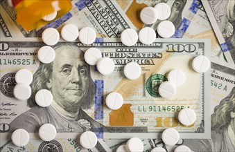 Medicine pills scattered on newly designed U.S. one hundred dollar bills