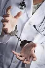 Female doctor or nurse in handcuffs wearing lab coat and stethoscope