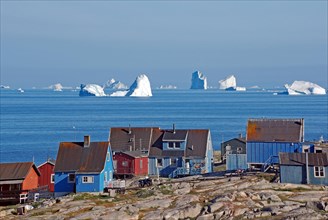 Wooden houses in front of huge icebergs