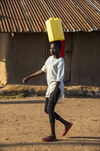 Woman carrying a water canister on her head bringing water home from Lake Albert