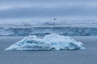 Helicopter flying over a very huge glacier on Mc Clintok or Klintok Island