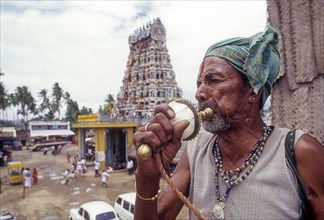 A Sadhu blowing a conch shell in front of Patteeswarar Swamy Temple at Perur in Coimbatore