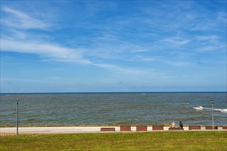 Resting benches with two people at the beach section protected by dikes at the Estdorf of the island Baltrum