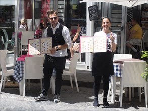 Waitress and waiter showing menu in front of an ice cream cafe