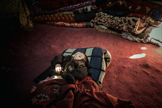 Toddler of a nomadic family lying on the floor in a yurt