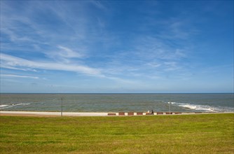 Resting benches with two people at the beach section protected by dikes at the Estdorf of the island Baltrum