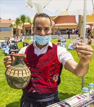 Employee with mask offers typical Cypriot liquor Zivania