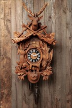 Original Black Forest cuckoo clock in front of rustic wooden wall